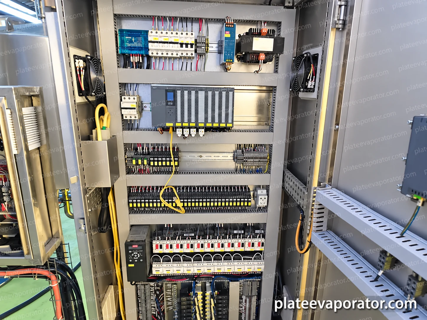 Open electrical cabinet showing PLC modules, terminals, switching equipment and wiring ducts